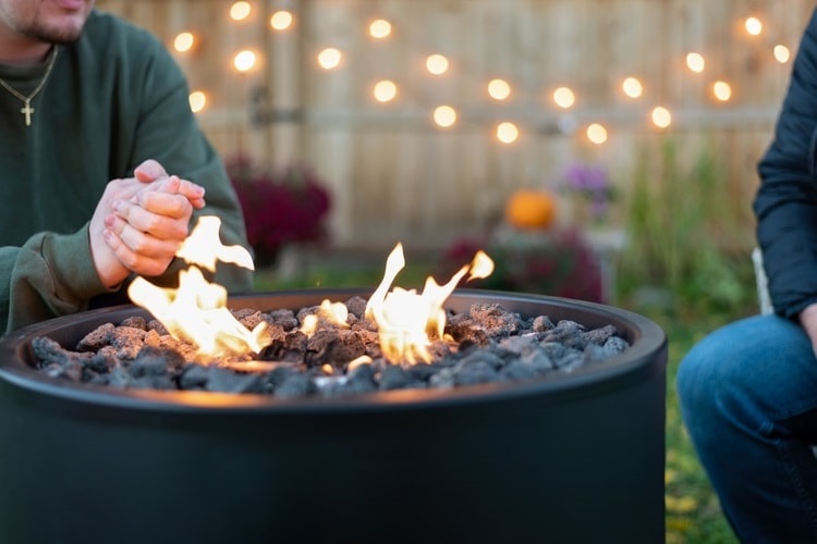 People warming hands around a propane fire pit